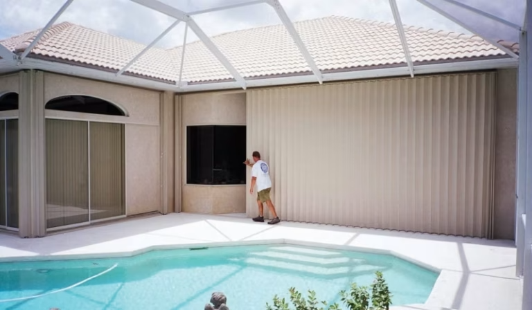 Accordion shutters installed on a covered patio by the pool