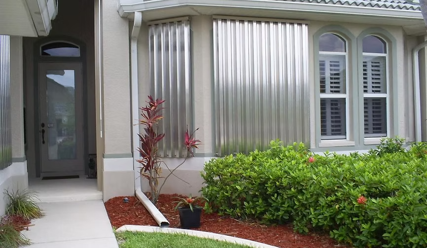 Hurricane panels on house windows beside an entry walkway
